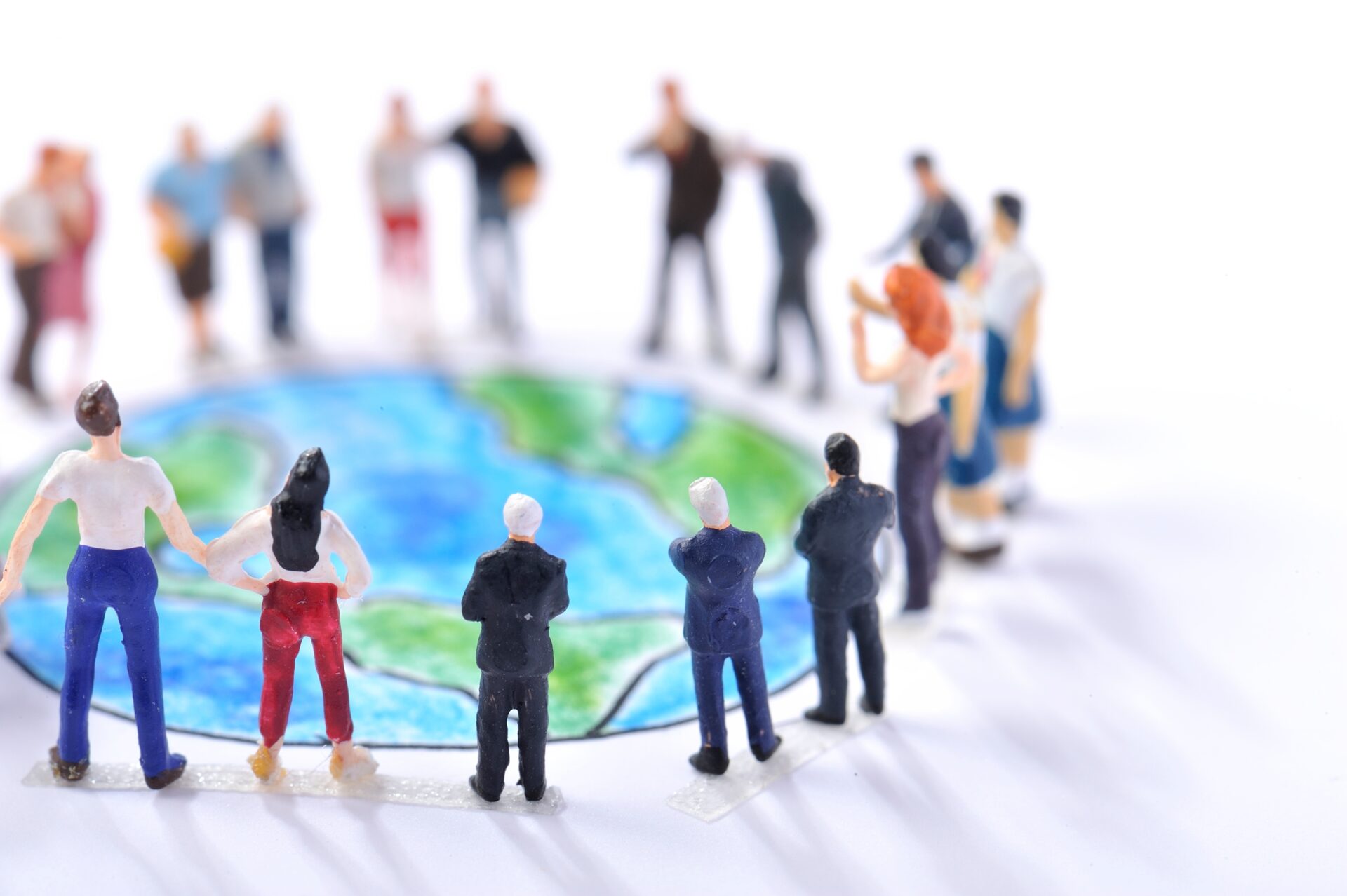 Energieberatung Bielefeld – Gemeinsam für unsere Erde: Verantwortung teilen, Zukunft gestalten Miniaturfiguren von Menschen stehen im Kreis um eine kleine Abbildung der Erde. Die Szene symbolisiert Gemeinschaft, Zusammenhalt und globale Verantwortung für den Schutz unseres Planeten.